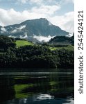 Clouds covering Stanserhorn alpine peak behind the waters of Alpnachersee. View from the northern bank of Alpnachersee mountain lake.