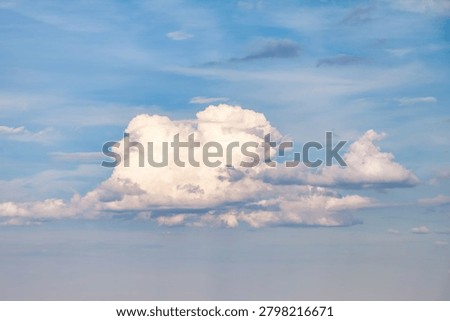 Clouds of different shapes are spread across a bright sky. The setting is outdoors, giving a clear view of the sky. This moment captures the beauty of nature in an open area.