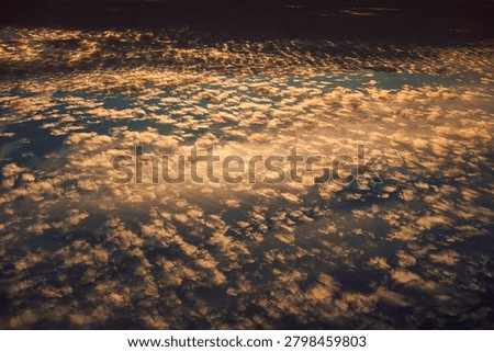 Clouds fill sky during sunset with mix of colors and patterns over horizon in evening.  large expanse  sky shows clouds during sunset. colors shift from blues to soft oranges. Light plays across clouds