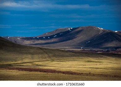 clouds float across the sky, forming a light-shadow pattern on the mountains