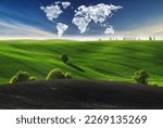 clouds in the form of a world map over a green field. Travel and landscape concept. hilly field