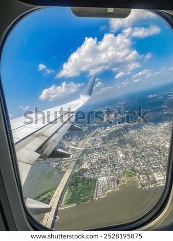 Clouds and highways outside of plane window on a sunny day with wing visible