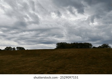 Clouds over a hill in a field