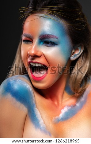 Clouds are painted on the face of the model. Girl with creative make up. emotions, narrowed eyes, open mouth