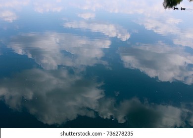 The Clouds Reflecting Off The Water Of The Lake On A Close Up View Of Water.