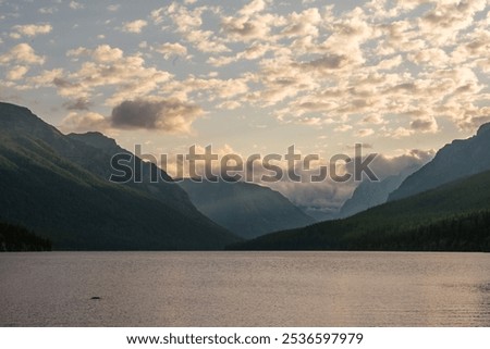 Clouds Roll Over Distant Mountains Behind Bowman Lake in Glacier