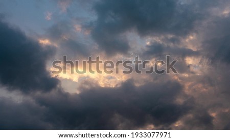 CLOUDS SHOWS THE IMPACT OF GLOBAL CLIMATE WARMING. Abstract clouds backgrounds. Dark dramatic clouds move fast. Ragged thunderclouds cover the sunny areas of the sunset sky.