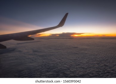Clouds and sky as seen through window of an aircraft. Looking through window aircraft during flight in wing with a nice blue/purple/orange sky.