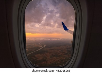 Clouds and sky as seen through window of an aircraft. Looking through window aircraft during flight in wing with a nice blue/purple/orange sky.