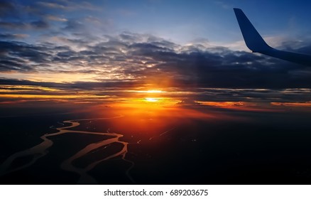 Clouds And Sky As Seen Through Window Of An Aircraft. Flying Over The Evening Timelapse Clouds With The Late Sun. Flight Through Moving Cloudscape With Beautiful Sun Rays.