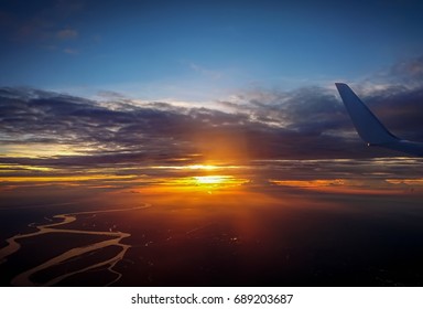 Clouds And Sky As Seen Through Window Of An Aircraft. Flying Over The Evening Timelapse Clouds With The Late Sun. Flight Through Moving Cloudscape With Beautiful Sun Rays.