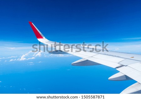 Clouds and sky as seen through window of an aircraft with airplane's wing