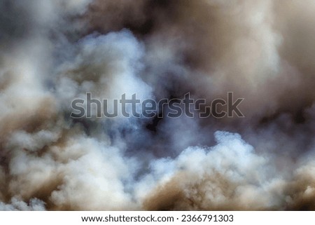Clouds of smoke over a burning island in the sea.