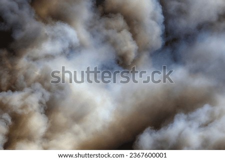 Clouds of smoke over a burning island in the sea.