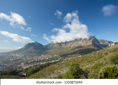 Clouds spilling over Table Mountain on a clear day, Cape Town, South Africa