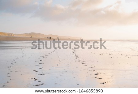The clouds started turning orange in a pale blue sky. Reflected in the wet sand it turned the beach into a dreamy mother of pearl landscape.