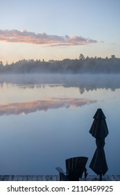 clouds at sunrise or sunset reflecting in calm tranquil water of cottage lake on holiday in northern Ontario in cottage country symmetrical shapes room for type vertical format  background backdrop