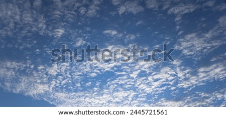 clouds with sunset of a summer day, the sky is painted in shades of blue, with clouds transitioning smoothly into light white tones, creating a gradient background. Sun rays  through the clouds bring