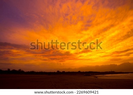 Clouds at sunset in tropical Broome, North Western Australia are beautifully hued with soft salmon pink, grey and  pale blue tones as the hot sun sinks into the Indian Ocean in the summer Wet Season.