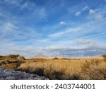 clouds sunshine and mountains line the view over the grasses and shrubs of the Clark County Wetlands Park in Henderson Nevada 