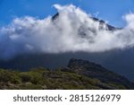 Clouds swirling around a sharp volcanic peak above scrub-covered slopes near Masca in the Teno massif