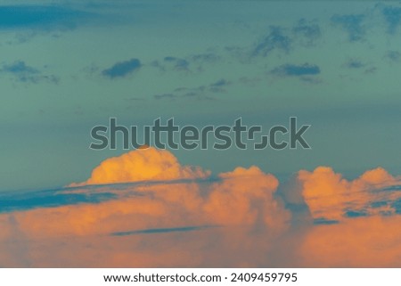 Clouds with unrealistically bright orange blue colors at sunset. Evening shades, atmospheric distortions, light transformation.
