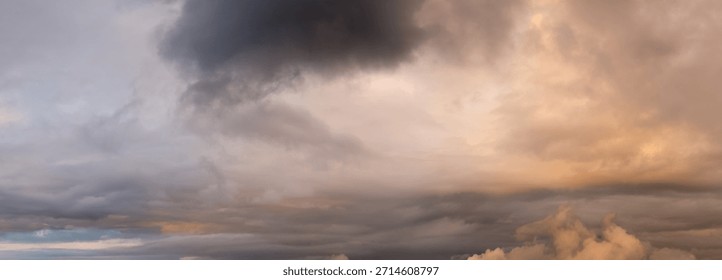 Cloudscape featuring a dramatic sunset sky with thick, dark clouds and warm orange hues over the horizon.
