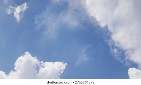 A cloudscape featuring white, fluffy clouds set against a clear blue sky.