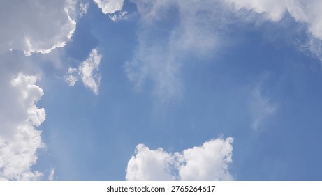 A cloudscape featuring white, fluffy clouds set against a clear blue sky.
