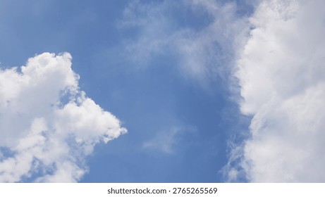 A cloudscape featuring white, fluffy clouds set against a clear blue sky.