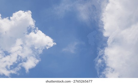 A cloudscape featuring white, fluffy clouds set against a clear blue sky.