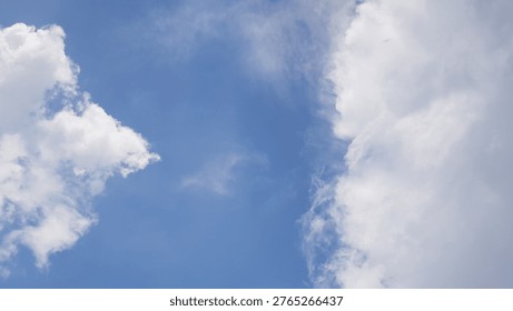 A cloudscape featuring white, fluffy clouds set against a clear blue sky.