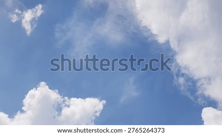 A cloudscape featuring white, fluffy clouds set against a clear blue sky.