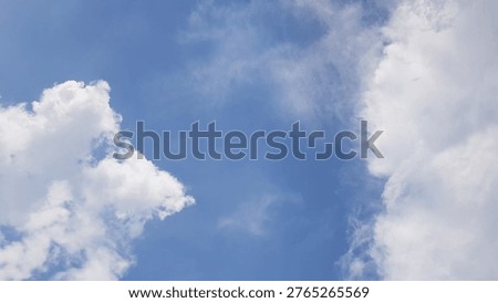 A cloudscape featuring white, fluffy clouds set against a clear blue sky.