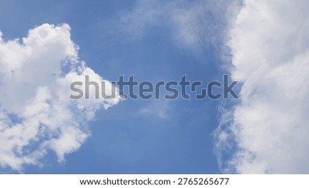 A cloudscape featuring white, fluffy clouds set against a clear blue sky.