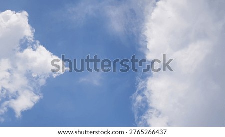 A cloudscape featuring white, fluffy clouds set against a clear blue sky.