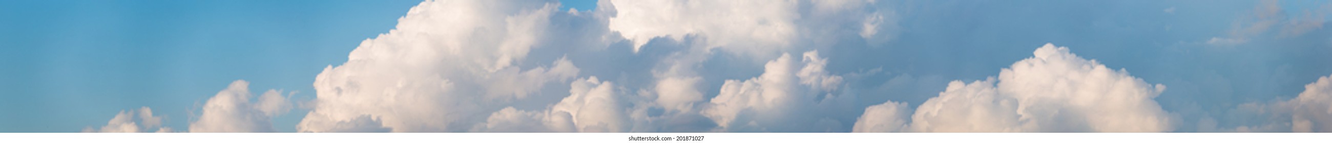 Cloudscape horizontal banner or panorama of beautiful fluffy white cumulus clouds in a sunny blue summer sky - Shutterstock ID 201871027