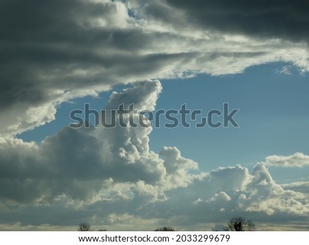 Cloudscape large  voluminous clouds with a pool of blue sky on a thunderous afternoon predicting a brewing storm