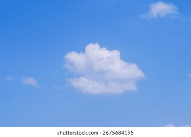 Cloudscape Serenity: A singular, fluffy cloud drifts gracefully against an expanse of vibrant azure, capturing the essence of tranquility.