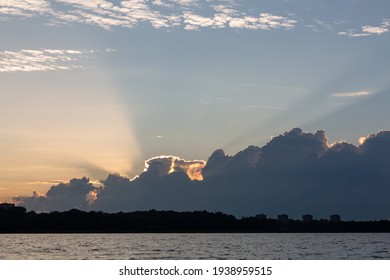 Cloudscape in summer at sunset on the lake and field