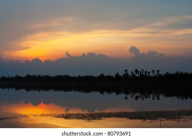 Cloudscape of sunset with orange and blue sky and lake.