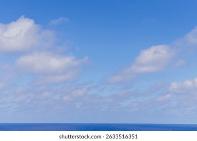 Cloudscape view over the Pacific Ocean with clear blue sky and fluffy clouds.
