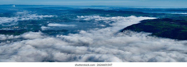 Cloudscape view over a valley with mountains and a lake during a clear day