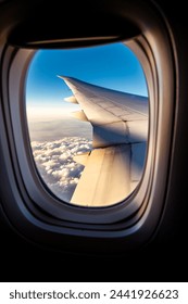 Cloudscape of window at flying airplane. View through an airplane porthole. A sunset landscape from an airplane window.