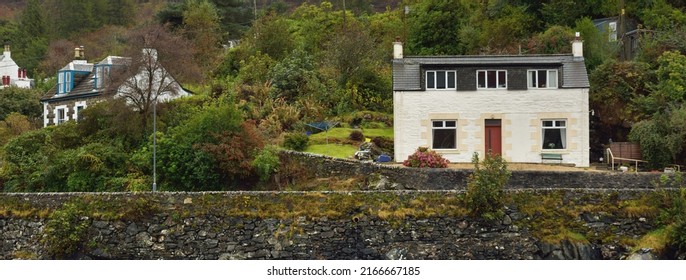 Cloudy autumn day. A view of the shores of Tarbert from the water. Country houses close-up. Scotland, UK