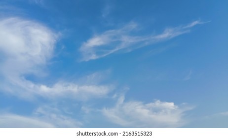 Cloudy blue sky background. Beautiful blue sky with wispy fluffy soft white clouds in sunny day. Elegant cloudy clear blue sky texture, wallpaper. Horizontal landscape image. Cirrus Clouds in sunlight