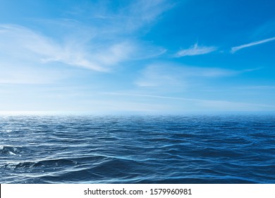 Cloudy Blue Sky Leaving For Horizon Above A Blue Surface Of The Sea