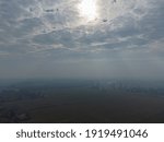 Cloudy blue sky with sun rays touching the farms and the city.