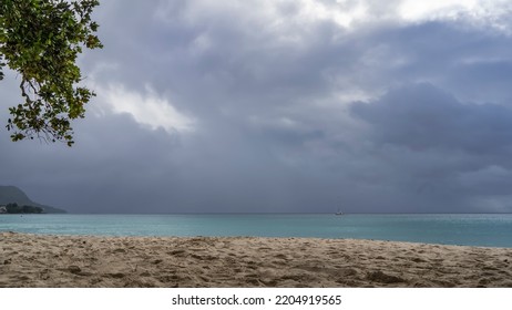Cloudy day on a tropical beach. Clouds over a turquoise calm ocean. Footprints in the sand. A green tree branch against the sky. Seychelles. Mahe Island. Beau Vallon - Shutterstock ID 2204919565