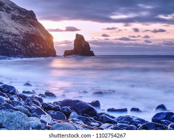 Cloudy evening on rocky shore at sunset. Sunset mirroring in  sea water and large cracked rocks with erosion marks Scotland, Sky Island, Talisker Bay.